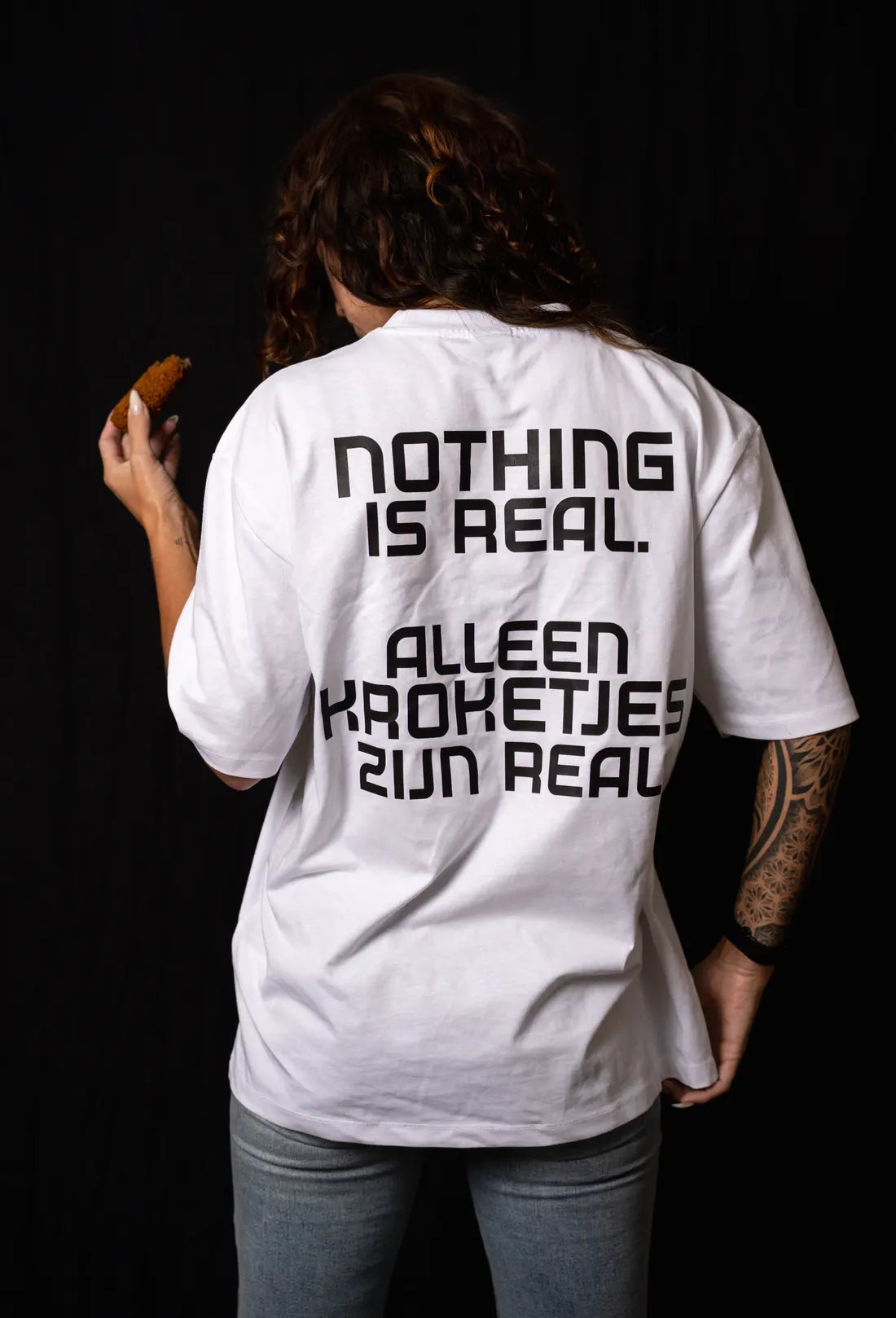 Vrouw van achteren, op de rug: Nothing is real. Alleen kroketjes zijn real.